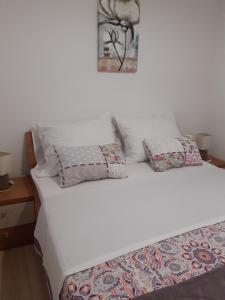 a bed with white sheets and pillows on it at Apartments Žerjav in Mali Lošinj