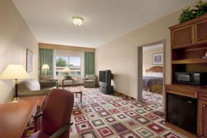 アルバニーにあるDays Inn & Suites by Wyndham Albanyのベッドとリビングルームが備わるホテルルームです。