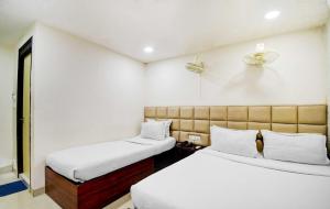 Habitación pequeña con 2 camas y paredes blancas. en Kyd Guest House Near Indian Museum en Calcuta