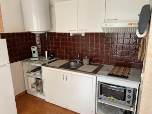 a small kitchen with white cabinets and a sink at La coquille - Appartement spacieux 45m2, T2 à 1min de la plage - WIFI in Valras-Plage