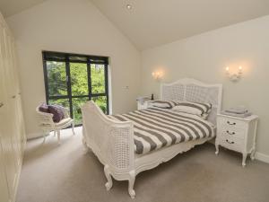 a white bedroom with a white bed and a window at Appletree Cottage in Fordingbridge