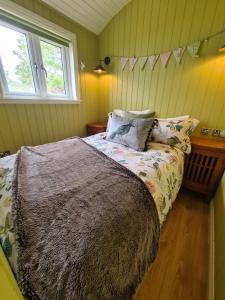 um quarto com uma cama com um cobertor e uma janela em The bay ,luxury shepherds hut, em Dundonnell
