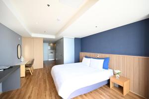 a bedroom with a large white bed and a blue wall at Kolon Seacloud Hotel in Busan