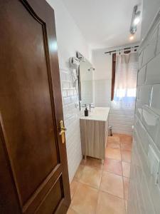 a bathroom with a sink and a wooden door at Apartamentos Villa Torcal in Villanueva de la Concepción