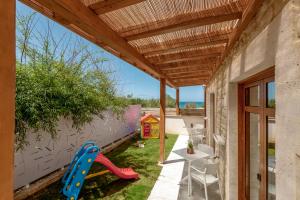 a small backyard with a wooden pergola and a table and chairs at Pileas Villa, a Supreme Retreat by the Βeach, By ThinkVilla in Pigianos Kampos