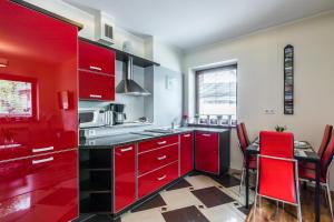 kuchnia z czerwonymi szafkami i stołem z czerwonymi krzesłami w obiekcie Czerwone Wierchy & Spa w Zakopanem