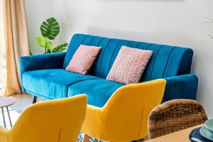 a blue couch in a living room with yellow chairs at Heart Location & PARKING in Málaga