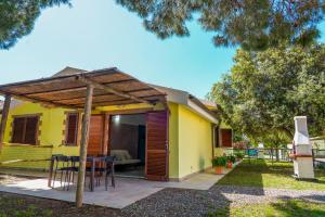 uma casa amarela com uma mesa e cadeiras num pátio em Agriturismo Il Roseto em Marina di Grosseto