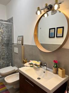 bagno con lavandino, servizi igienici e specchio di Bnbook Casa Luccio VistaLago Ispra a Ispra