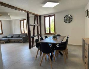 a dining room with a table and chairs and a clock at Gîte du Charme - atypique et chaleureux in Baldenheim