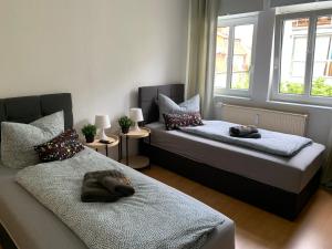 a bedroom with two beds and two windows at Jena City Apartment, Balkon, sonnig, Wifi, Parkplätze, Nähe Zentrum in Jena