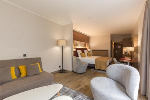 a hotel room with a bed and a couch and chairs at Leonardo Hotel Antwerpen in Antwerp