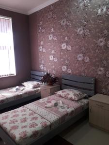 2 Betten in einem Schlafzimmer mit rosafarbener Blumentapete in der Unterkunft ERA Hotel in Gjumri