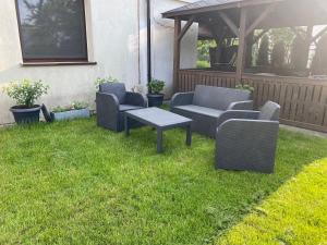 a patio with chairs and a table on the grass at Pokoje na Wczasowej w Sztutowie in Sztutowo