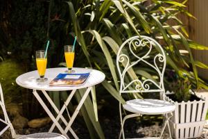 - deux verres de jus d'orange sur une table avec deux chaises dans l'établissement Delight Corfu Apart Hotel, Sidari, à Sidari
