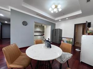 een keuken en eetkamer met een witte tafel en stoelen bij Vinhomes Royal City Apartment 3 Br in Hanoi
