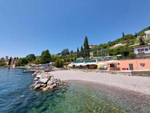 una playa con rocas en el agua y edificios en Pizzocolo resort fasano, en Gardone Riviera