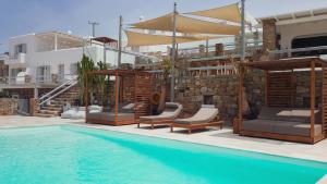 einen Pool mit Stühlen und Sonnenschirmen neben einem Gebäude in der Unterkunft Senses Luxury Suites & Villas in Elia