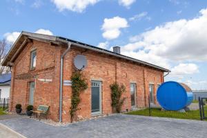 Un edificio de ladrillo rojo con un gran objeto azul al lado. en Ferienhaus am Hafen, en Stahlbrode