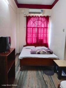 Bikash Bhawan Lodge في سيليغري: غرفة نوم بسرير ونافذة حمراء