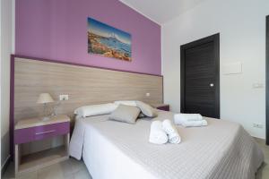 a bedroom with a white bed and a purple wall at L'Orto del Conte in Naples