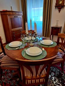 a wooden table with plates and wine glasses on it at Weisz Castle style Apartment - With Free Private Parking,Wifi in Carei