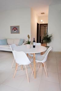 biała jadalnia z białym stołem i krzesłami w obiekcie Oasis Garden House w mieście Iraklitsa