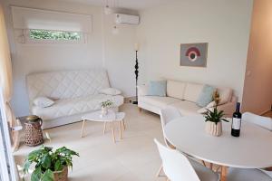 a living room with a white couch and a table at Oasis Garden House in Iraklitsa