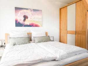 una camera da letto con un grande letto con lenzuola bianche di Ferienwohnung Sonnenaufgangsgenuss Harriersand a Schwanewede