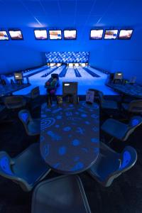 eine Bowlingbahn mit Tisch und Stühlen in einem blauen Raum in der Unterkunft Hotel Porto in Plungė