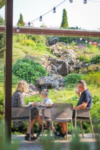 una familia sentada en una mesa en un jardín en Hotel Porto, en Plungė