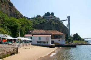 una spiaggia con un ristorante e un edificio vicino all'acqua di Lisbon South Bay modern apartment with river view ad Almada