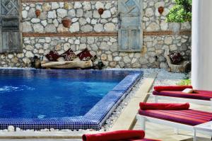 a swimming pool with two lounge chairs next to a stone wall at Villa Kirmizi Lale, Private Pool, Gardens, Very Close to Town - No Need for Taxi in Kas