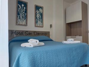 リド・ディ・カマイオーレにあるHotel San Domingoのベッドルーム1室(ブルーベッド1台、タオル付)