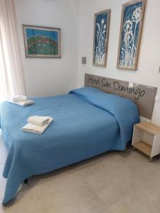 un letto blu in una camera da letto con un cartello sopra di Hotel San Domingo a Lido di Camaiore