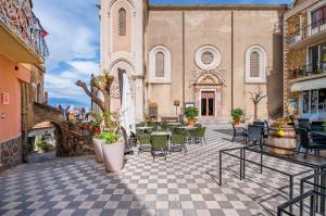 a courtyard with tables and chairs and a church at Castelmola Casa Chiocciola with Terraces in Castelmola