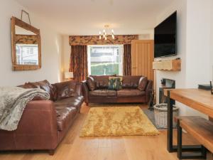 sala de estar con sofá de cuero y TV en Ananda House, en Windermere
