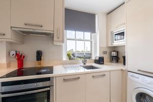 una cucina bianca con lavandino e lavastoviglie di Hyde Park Apartments a Londra