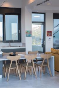 a dining room with tables and chairs and windows at Villa Rona Lefkada in Sivota