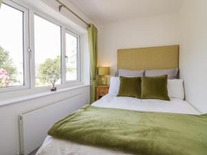 a bedroom with a bed with green sheets and windows at Ananda House in Windermere