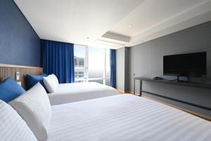 a hotel room with two beds and a flat screen tv at Kolon Seacloud Hotel in Busan