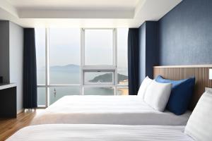 a bedroom with two beds and a large window at Kolon Seacloud Hotel in Busan +88 photos