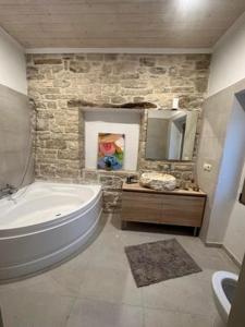 a bathroom with a large white tub and a stone wall at Villa Nikolas - Secluded and luxurious in Oziás