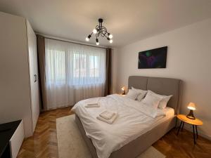 a bedroom with a bed with white sheets and a window at ESI Apartments #Central in Timişoara