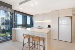 a kitchen with two bar stools and a refrigerator at ULTIQA Signature at Broadbeach in Gold Coast
