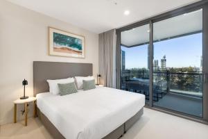 a bedroom with a white bed and a large window at ULTIQA Signature at Broadbeach in Gold Coast