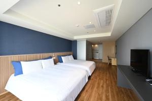 a hotel room with two beds and a television at Kolon Seacloud Hotel in Busan