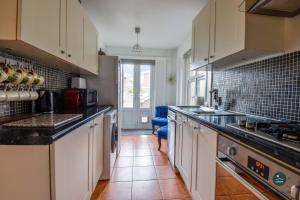 a kitchen with white cabinets and a tile floor at Bowleaze Hideaway - beachside dog friendly in Weymouth