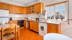 a kitchen with wooden cabinets and a table and a washer at Luminous 3BDR Apartment W/Balcony by LovelyStay in Vila Nova de Cacela