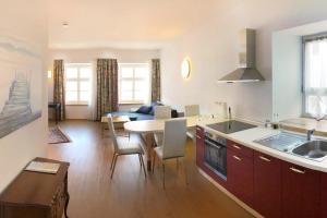 cocina y sala de estar con mesa y sillas en Hotel Freischütz Apartments, en Landshut